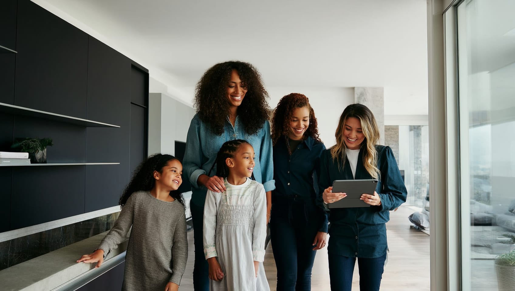 A family touring a home with their agent, who is showing them details on a tablet